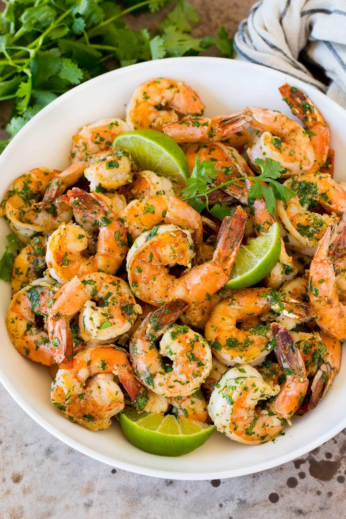 Cilantro Lime Shrimp | Seared Shrimp | Mango Salsa #salsa #shrimp #dinner #appetizer #fuyos A serving bowl of cilantro lime shrimp with lime wedges in it.