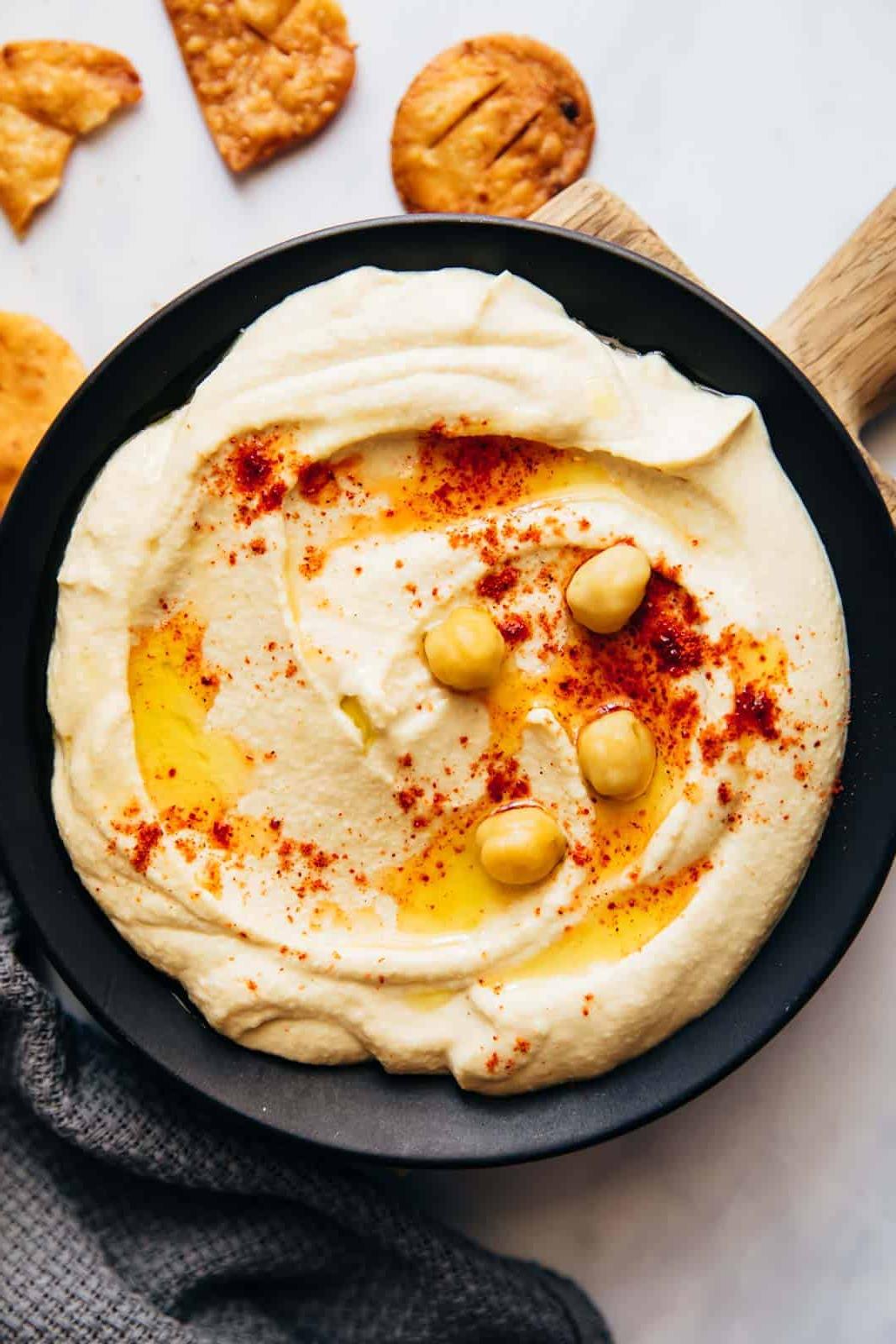Come preparare l'Hummus a casa leggero e soffice 2 Hummus servito in un piatto con pita fritta, olio d'oliva e ceci