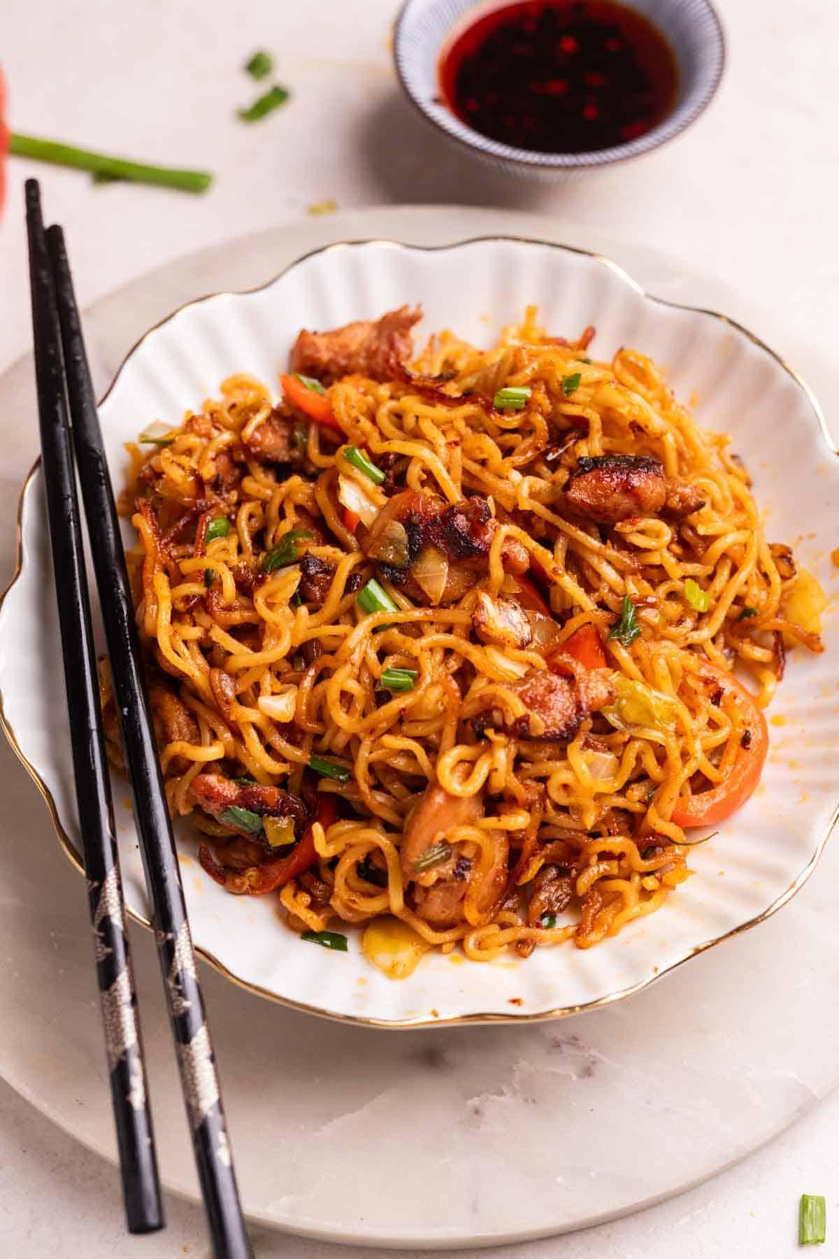 Noodles al Pollo Piccante | Noodles al Pollo con Olio di Peperoncino 2 noodles di pollo al peperoncino serviti in una ciotola bianca con bacchette e salsa di soia