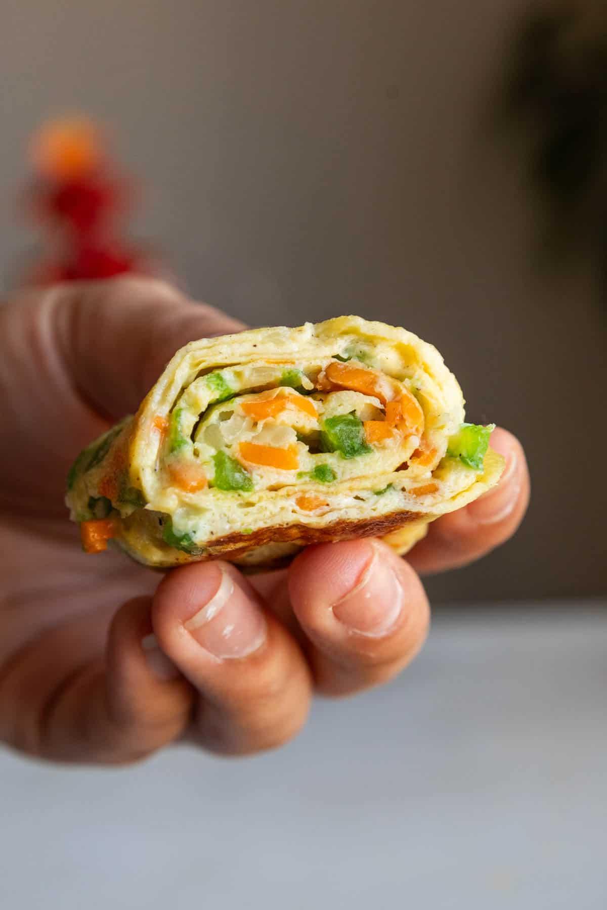 Involtini di Omelette Coreani 2 Primo piano di un rotolo di frittata coreano tenuto in mano