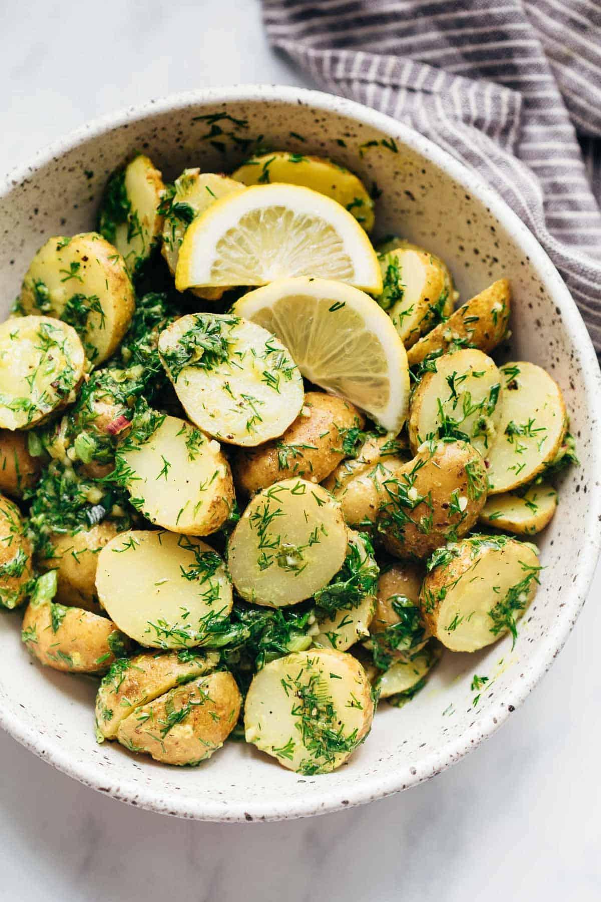 Insalata di Patate Salutare al Limone e Aneto (Senza Maionese) 2 Insalata di Patate Leggera al Limone e Aneto (senza maionese) servita in una ciotola bianca maculata con spicchi di limone