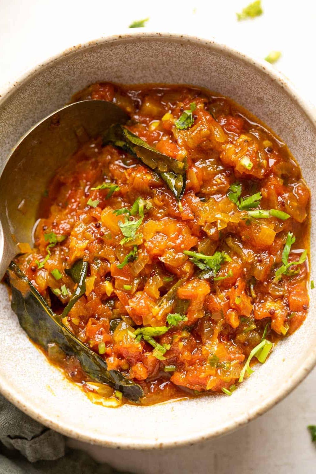 Chutney di Pomodoro – 2 Modi 2 Chutney di pomodoro in stile Nord Indiano servito in una ciotola di ceramica con un cucchiaio a lato
