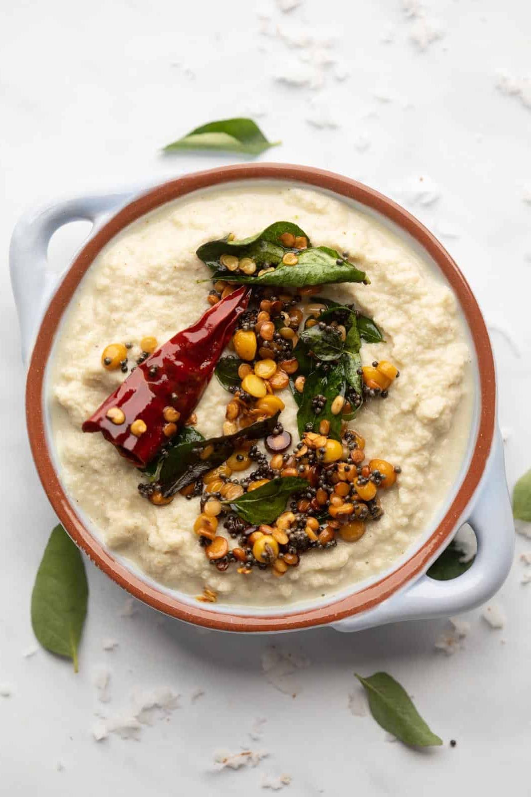 Ricette di Chutney per Idli e Dosa 3 Chutney di Cocco servito in una ciotola azzurra con condimento sopra