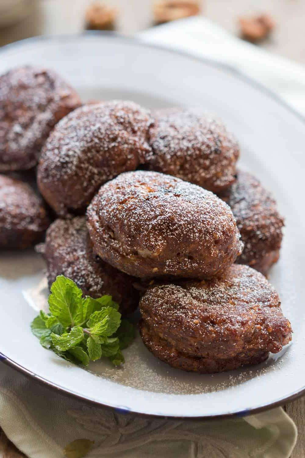 Frittelle di Banana, dettaglio ravvicinato delle consistenze primo piano delle frittelle servite su un piatto bianco, guarnite con foglie di menta