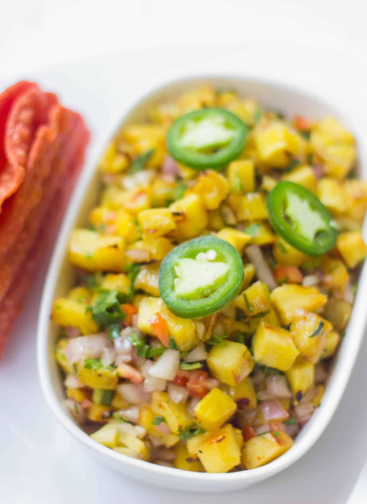 Salsa Piccante di Ananas Grigliato 4 Salsa Piccante di Ananas Grigliato guarnita con Jalapeño e servita in un piatto bianco.