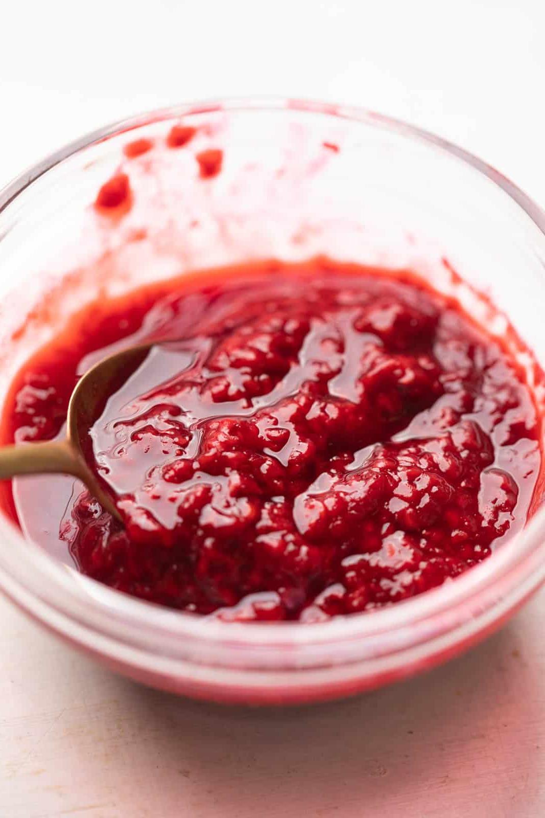 Come fare la Panna Cotta – Vaniglia Classica! 4 Coulis di lamponi in una ciotola con un cucchiaio