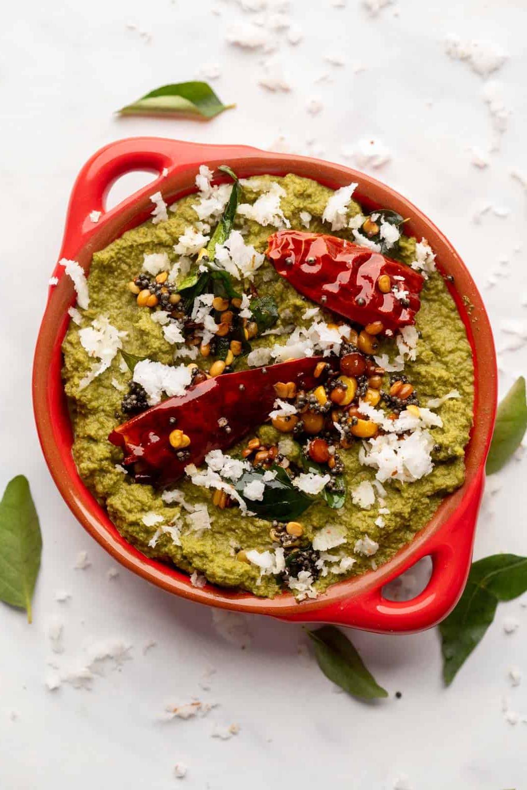 Ricette di Chutney per Idli e Dosa 5 Chutney di Cocco e Coriandolo servito in una ciotola rossa con condimento sopra