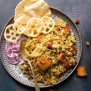 Riso Bath di Kavitha Aunty 6 Rice bath served in a grey plate with fryums, poppdum and onions on the side