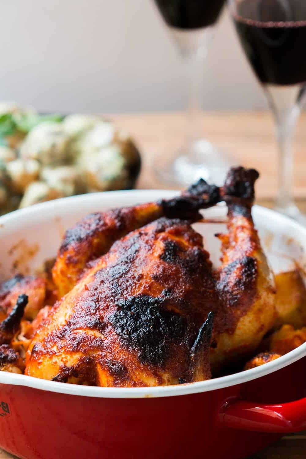 Pollo Arrosto Intero al Masala all'Indiana 6 Pollo arrosto indiano servito su un letto di cipolle, patate e aglio in una teglia rossa