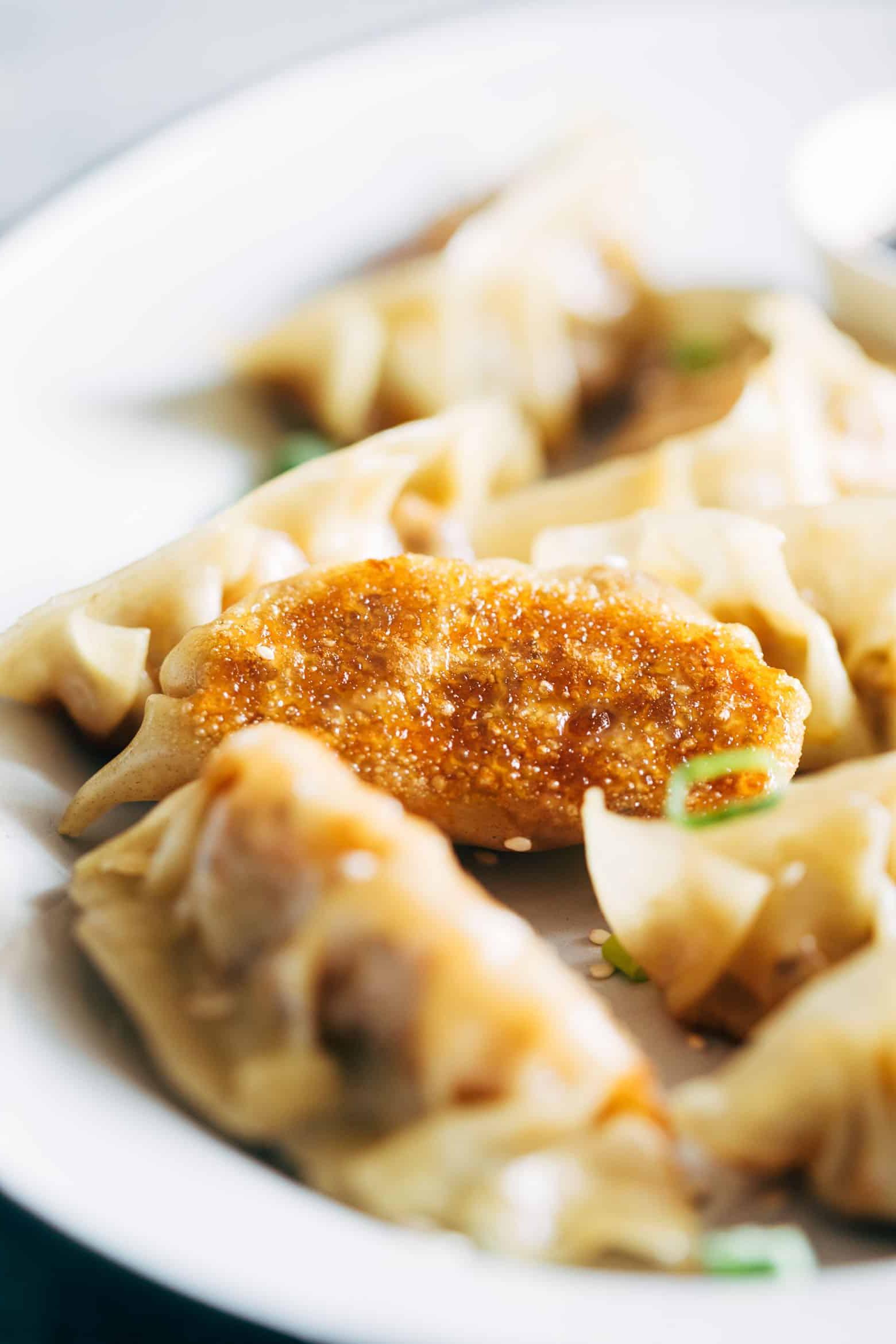 Gyoza Vegetariani con Carote e Paneer 6 Una mano che tiene un gyoza vegetariano appena cotto, mostrando la base croccante e il bordo delicatamente piegato.