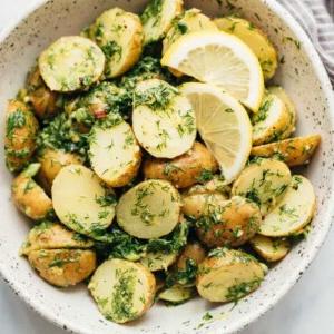 Insalata di Patate Salutare al Limone e Aneto (Senza Maionese) 6 Insalata di Patate Leggera al Limone e Aneto (senza maionese) servita in una ciotola bianca maculata con spicchi di limone