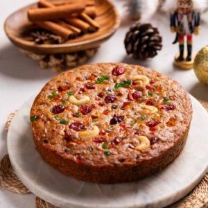 Plumcake Senza Uova 7 Immagine in miniatura di una torta di prugne senza uova appena sfornata e intera, splendidamente dorata, con frutta secca in cima.