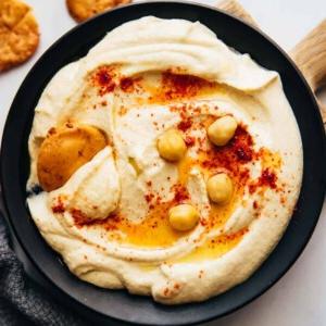 Come preparare l'Hummus a casa leggero e soffice 8 Hummus servito in un piatto con pita fritta, olio d'oliva e ceci