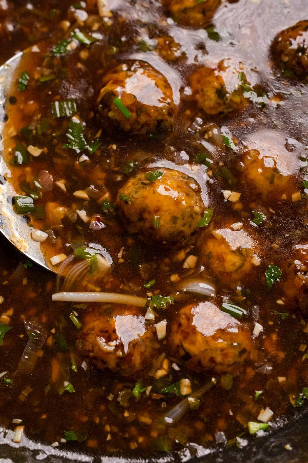 Manchurian Vegetariano | Come preparare il Manchurian 8 Primo piano del Manchurian Vegetariano in un wok con una schiumarola a lato