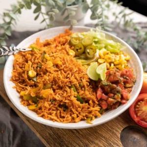 Riso Messicano in Pentola a Pressione (Arroz Rojo) 8 Riso messicano Instant Pot servito in una ciotola con lattuga, mais, salsa, jalapeños e spicchi di lime sul lato.