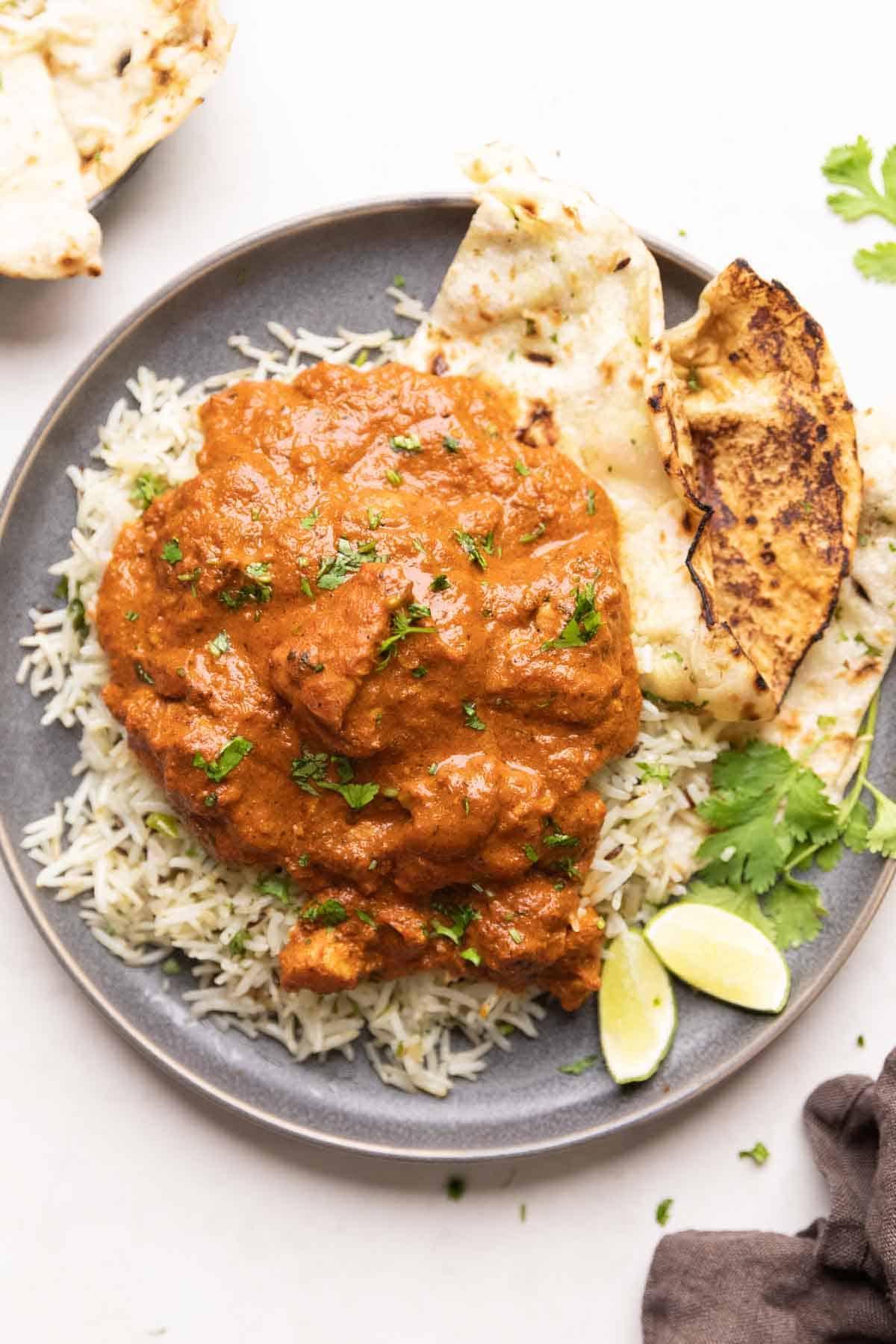 Instant Pot Pollo Tikka Masala 8 Un piatto di riso jeera guarnito con pollo tikka masala e un contorno di naan