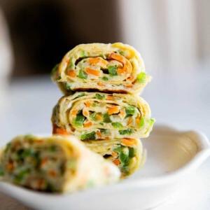 Involtini di Omelette Coreani 9 Primo piano di un rotolo di frittata coreana impilato uno sopra l'altro in una ciotola bianca