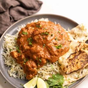 Instant Pot Pollo Tikka Masala 9 Un piatto di riso jeera guarnito con pollo tikka masala e un contorno di naan
