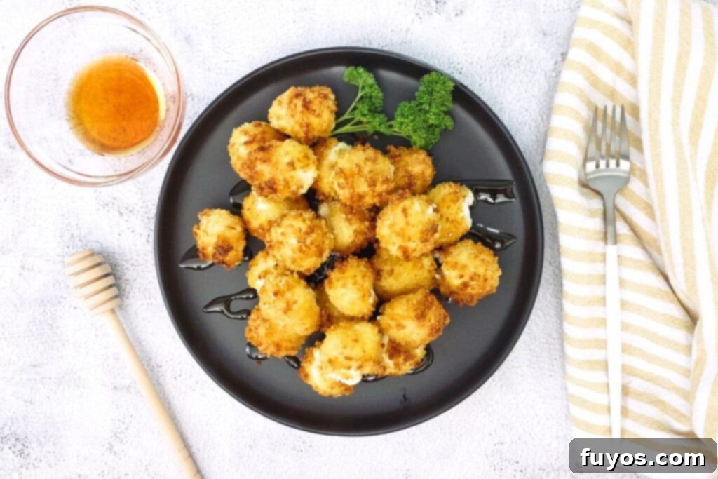 Air Fryer Goat Cheese Balls Crunchy Creamy Delight 12 Overhead view of air fryer goat cheese balls on a plate with hot honey for dipping.