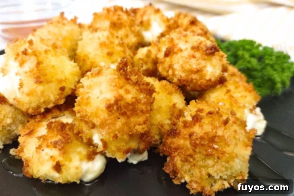 Air Fryer Goat Cheese Balls Crunchy Creamy Delight 13 Close up of golden browned air fryer goat cheese balls stacked on a plate, ready to be served.