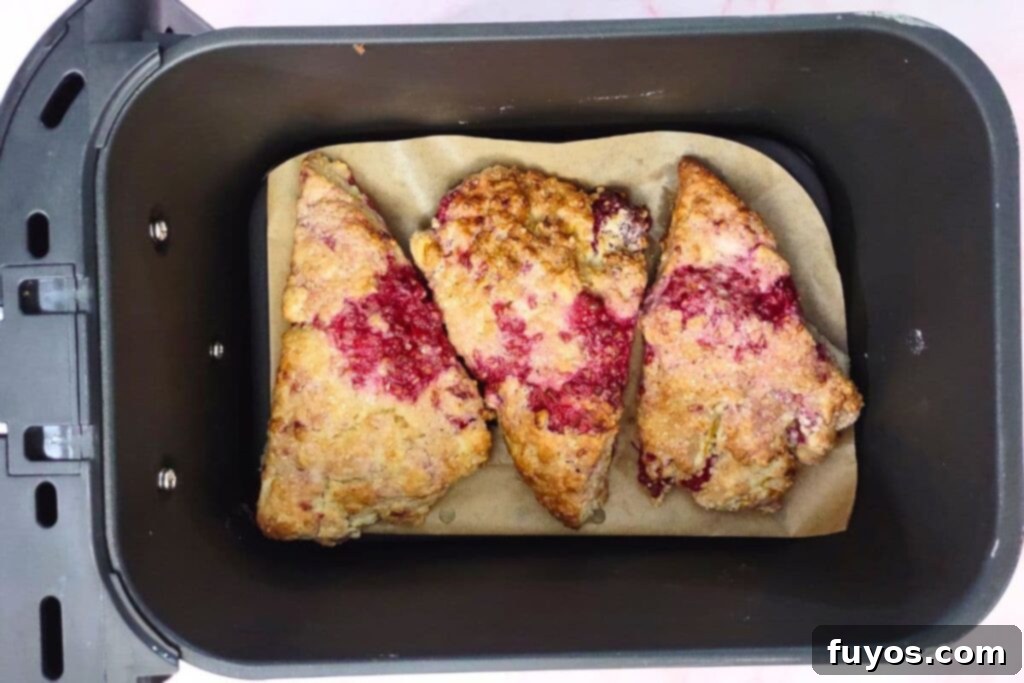 Golden brown raspberry orange scones in an air fryer basket after cooking