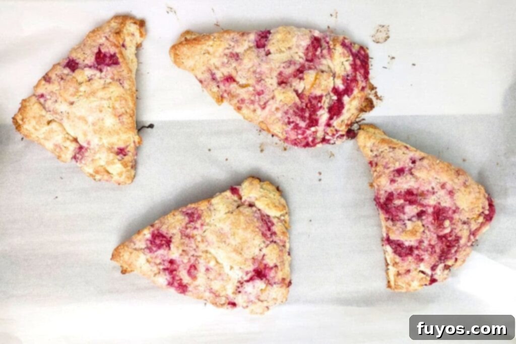 Oven-baked raspberry orange scones with golden brown edges on a baking sheet