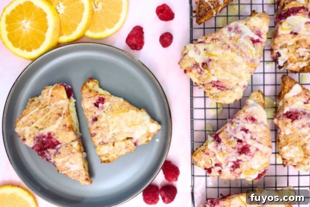 Overhead view of glazed raspberry orange scones arranged on a plate and a cooling rack