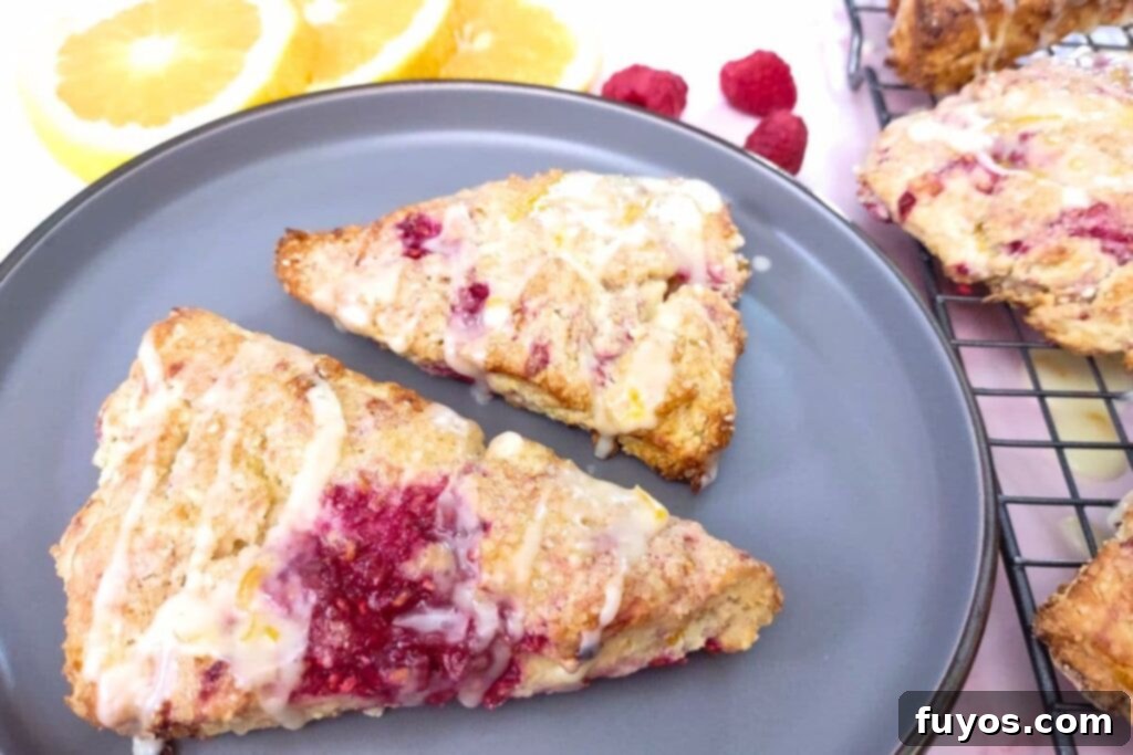 Two warm raspberry orange scones with glaze on a white plate