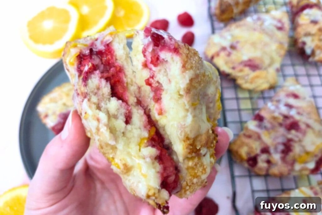 A freshly baked raspberry orange scone, split in half to show the fluffy interior and fruit pieces