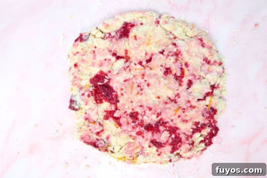 Flattening scone dough into a 1-inch thick circular shape on a floured surface