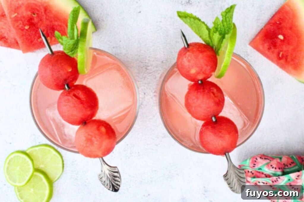 overhead view of two watermelon gin fizz drinks with three melon ball skewer, mint, and fresh lime