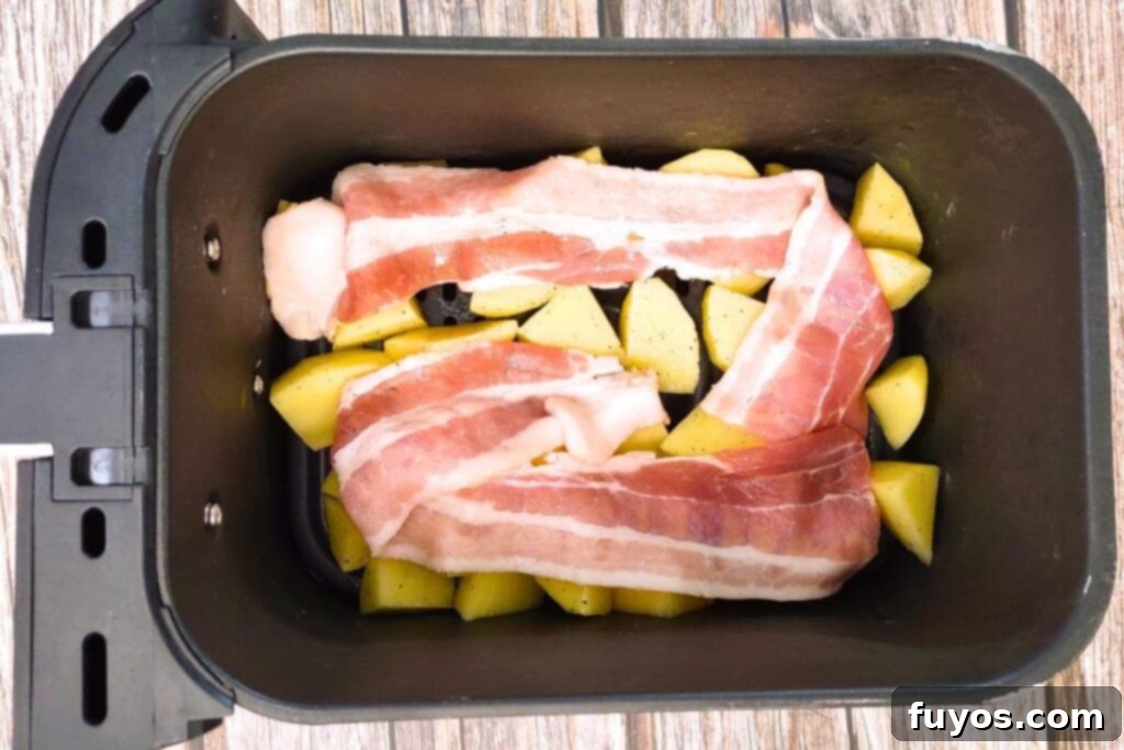 Place seasoned potatoes and bacon strips in the air fryer basket