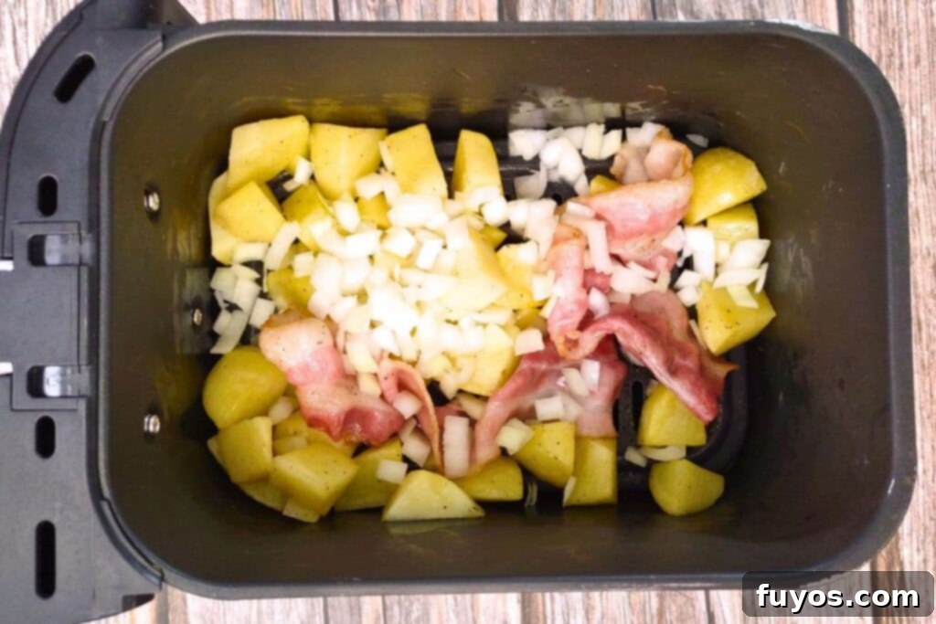 After cooking potatoes and bacon for a bit, add onions to the air fryer