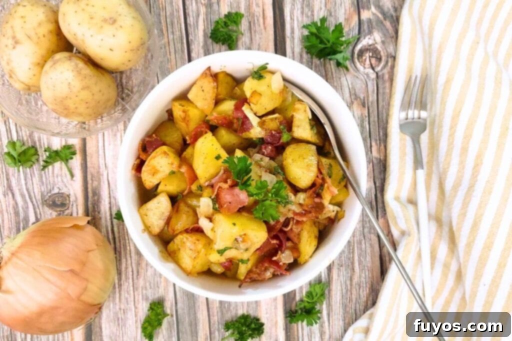 Overhead view of a white bowl filled with air fryer German potato salad, ready to serve.