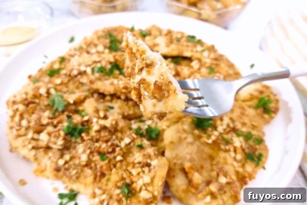 holding up a piece of air fryer pretzel crusted chicken on a fork