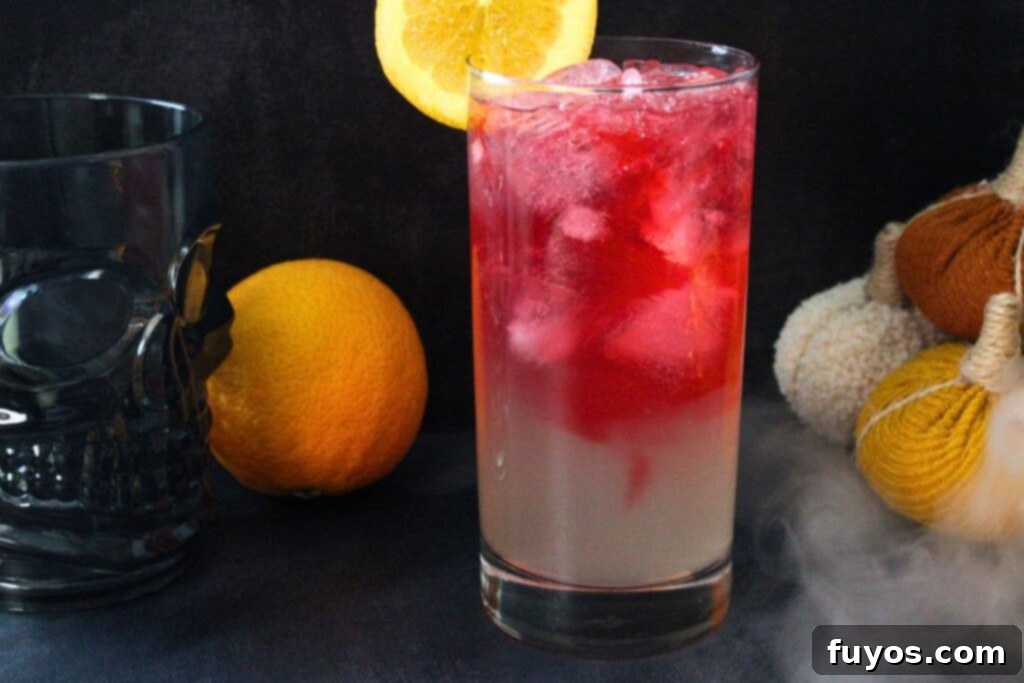 A Headless Horseman cocktail against a dark, misty background, highlighting the red bitters topping.