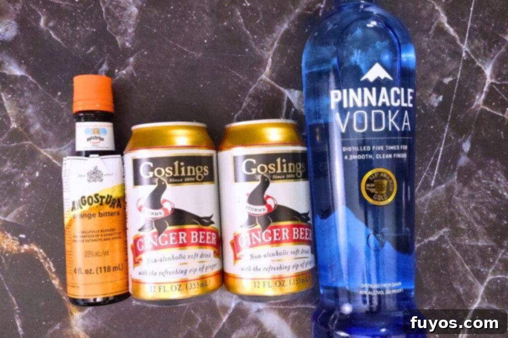 Ingredients laid out on a dark surface, including vodka, ginger beer, bitters, and an orange slice, ready to make a Headless Horseman cocktail.