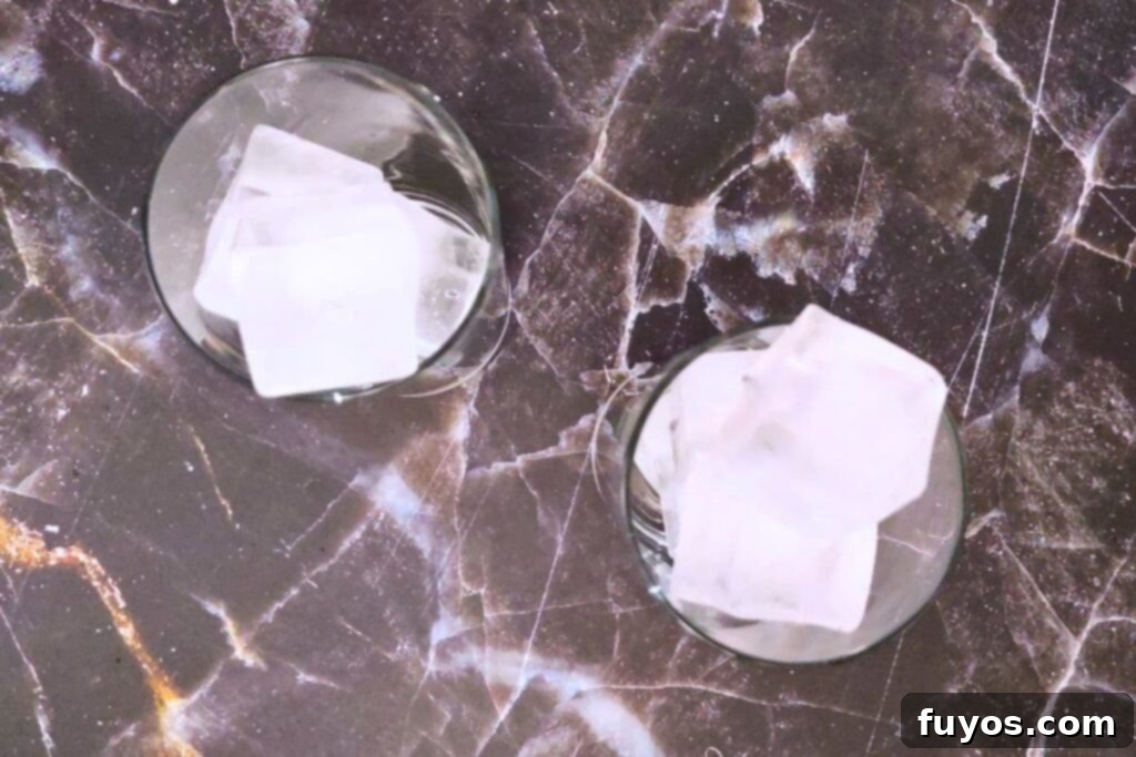 A glass being filled with ice cubes, the first step in making the Headless Horseman cocktail.
