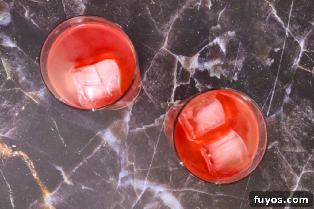 Red-colored bitters being slowly dripped onto the surface of the cocktail, creating the Headless Horseman effect.