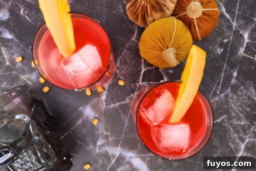 An overhead view of two finished Headless Horseman cocktails, garnished with orange slices and ready to serve.