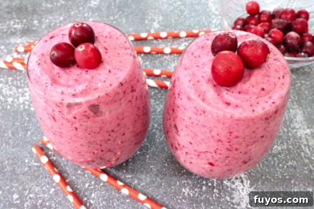 two glasses of cranberry banana smoothie with fresh cranberry on top