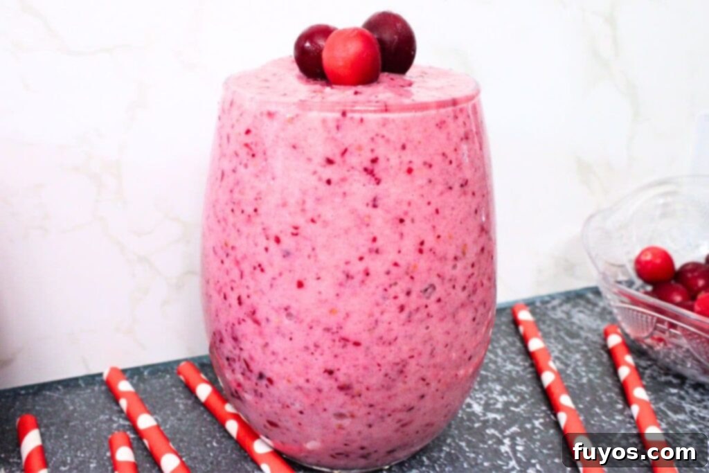 cranberry banana smoothie in a glass against a white marble background