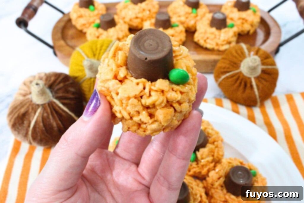 Balkabağı Rololu Pirinç Patlağı Barı: Sonbahar Keyfi 3 holding up a gooey pumpkin rice krispie treat