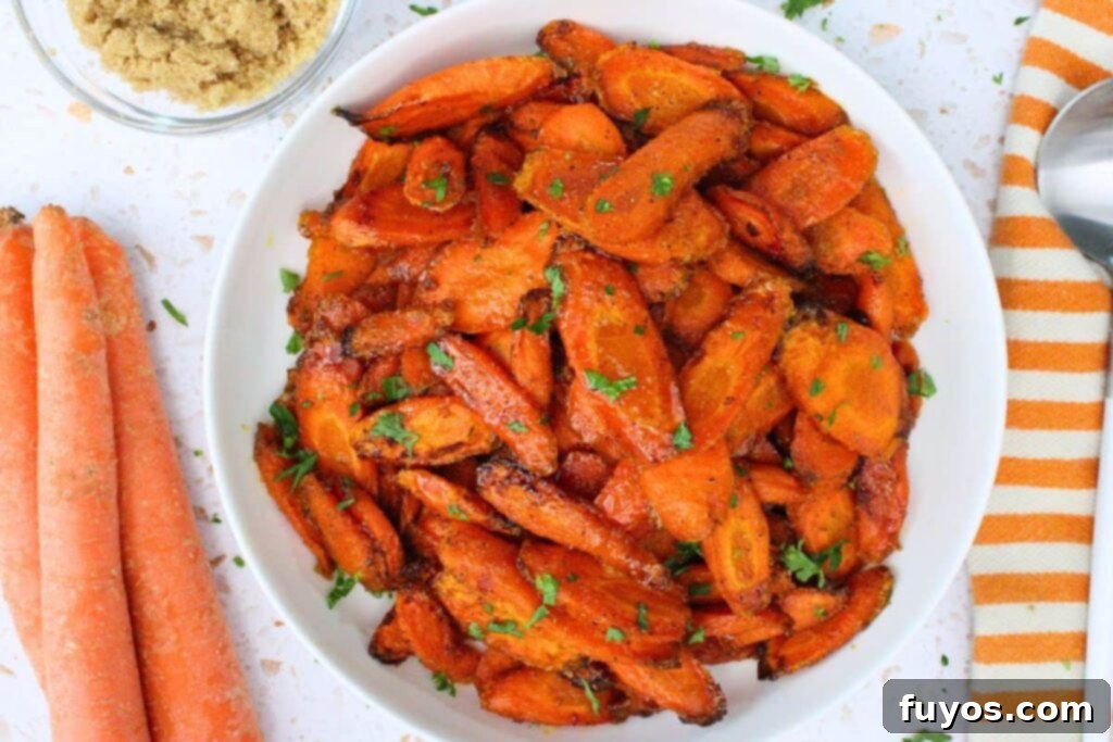 Delicious Air Fryer Brown Sugar Carrots Done in Ten Minutes 8 overhead view of air fryer brown sugar carrots in a white bowl next to fresh carrots and a serving spoon