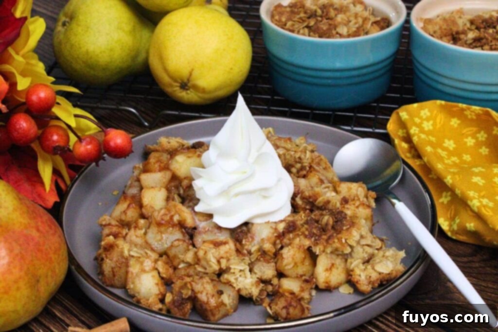 20-Minute Air Fryer Pear Crisp for Fall 9 air fryer pear crisp with a whipped cream dollop on a plate with a spoon and fresh pears in the background