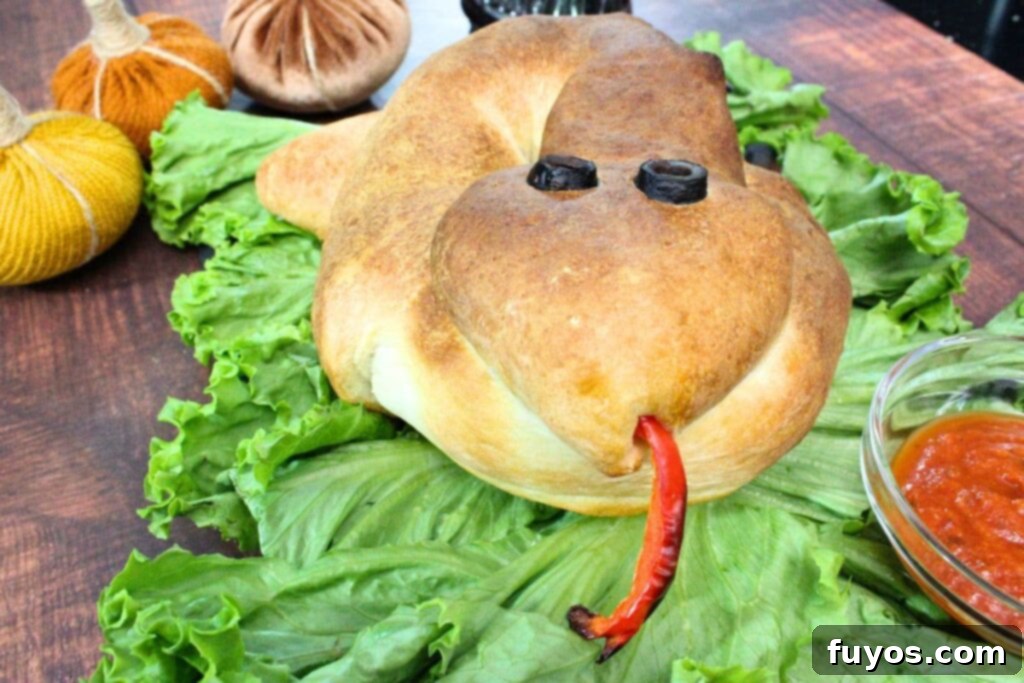 Air Fryer Serpent Bites: Your Halloween Party Hit 16 snake calzone on a bed of lettuce facing the camera with red pepper tongue sticking out