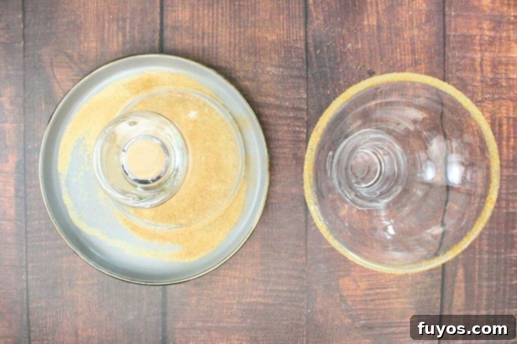 The first step of making a spiced pear margarita, showing a glass rimmed with a sugar and cinnamon mixture.