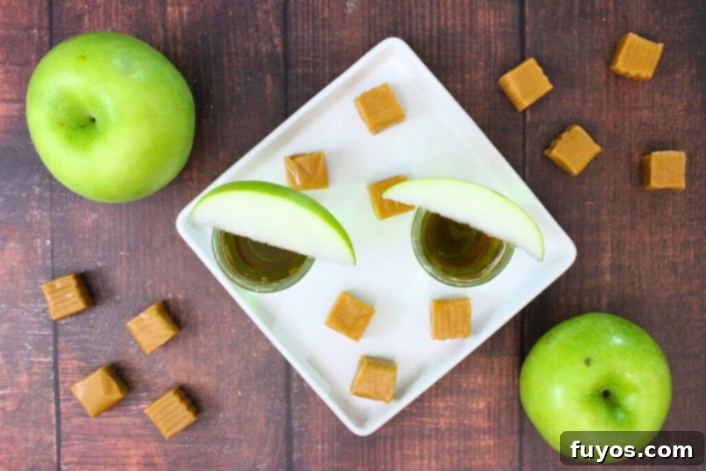 Simple Caramel Apple Crown Shot 7 overhead view of two caramel apple shots with crown next to caramel squares and fresh apples