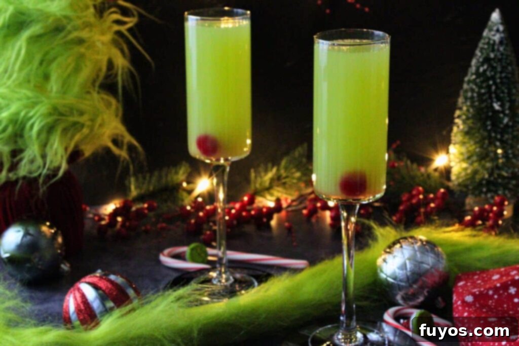 Three Ingredient Grinch Whoville Mimosas 8 two grinch mimosas in a holiday scene with christmas lights, ornaments, and grinch garland