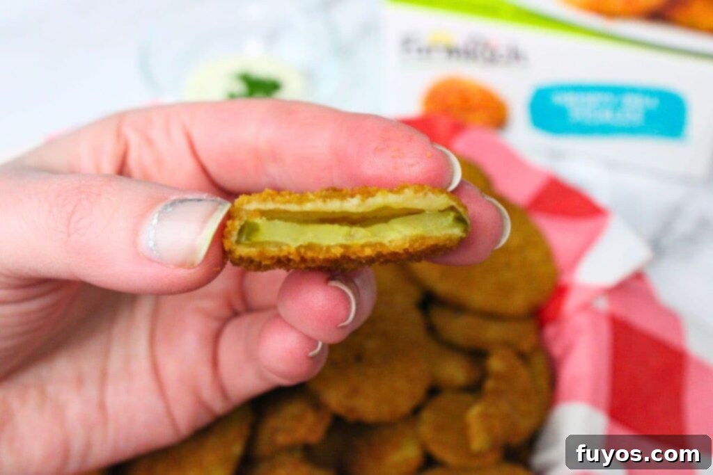 holding up half of an air fryer frozen fried pickle to show the inside
